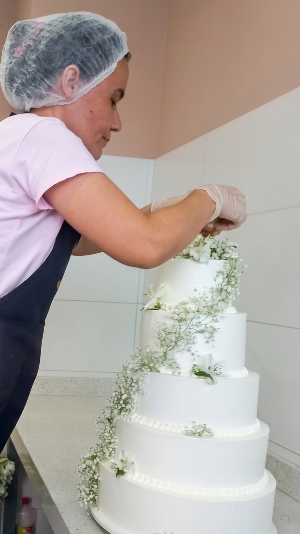Confeiteira decorando bolo artesanal em sua cozinha